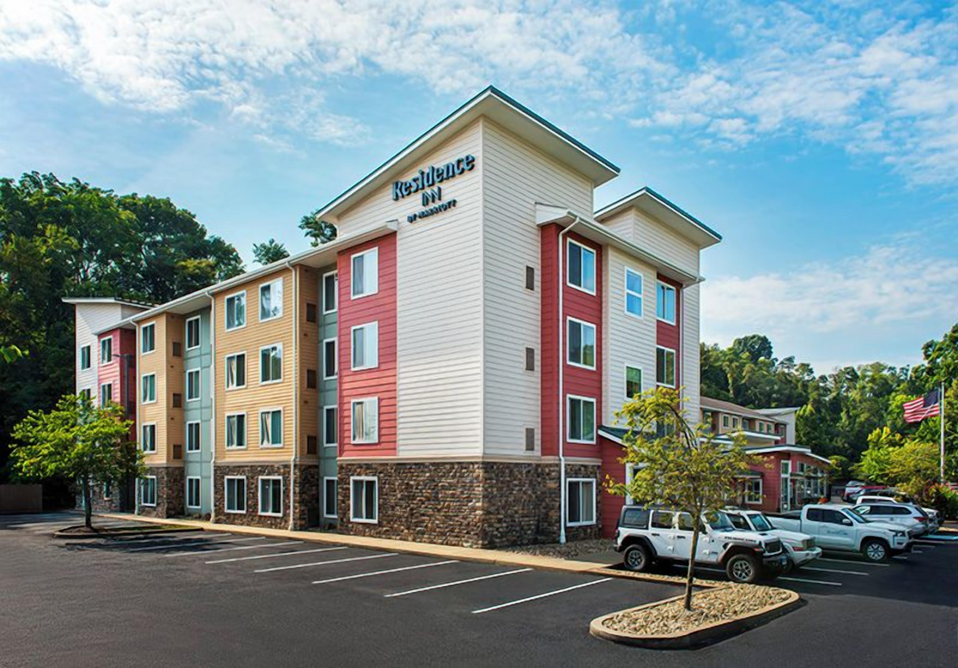 A multi-story hotel with a parking lot and several vehicles.