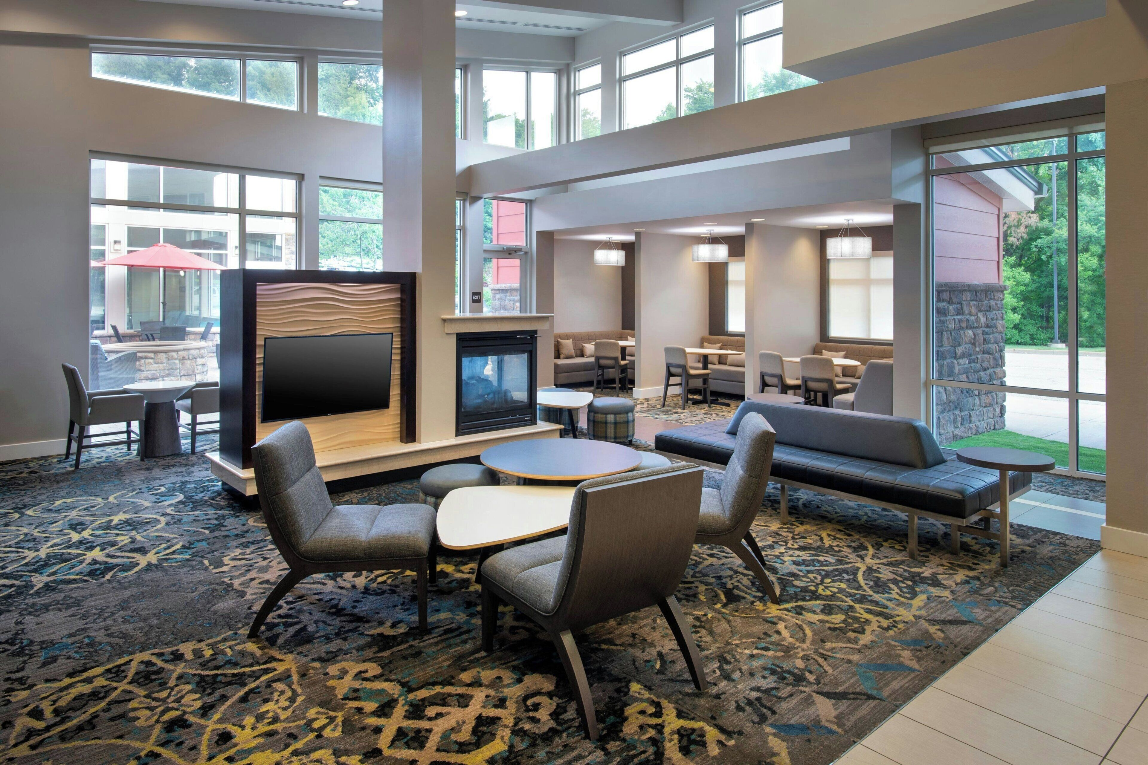 A hotel lobby with a fireplace, seating area, and large windows.
