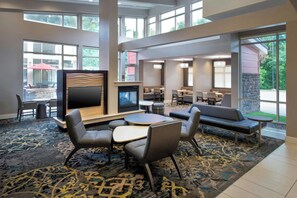 A hotel lobby with a fireplace, seating area, and large windows. - Residence Inn by Marriott Pittsburgh Monroeville/Wilkins (Pittsburgh)