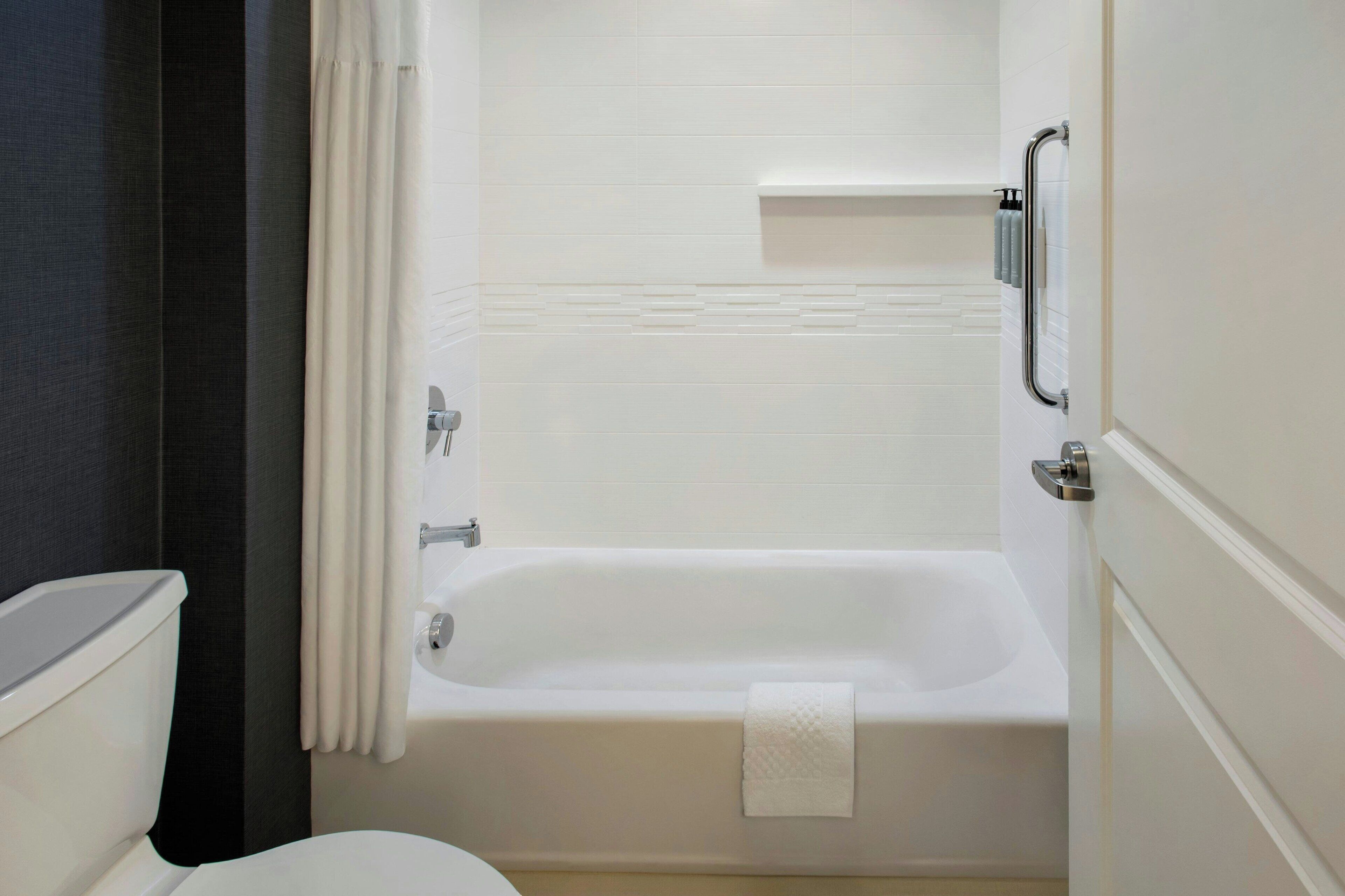 A bathroom with a white bathtub, a toilet, and a shower curtain.