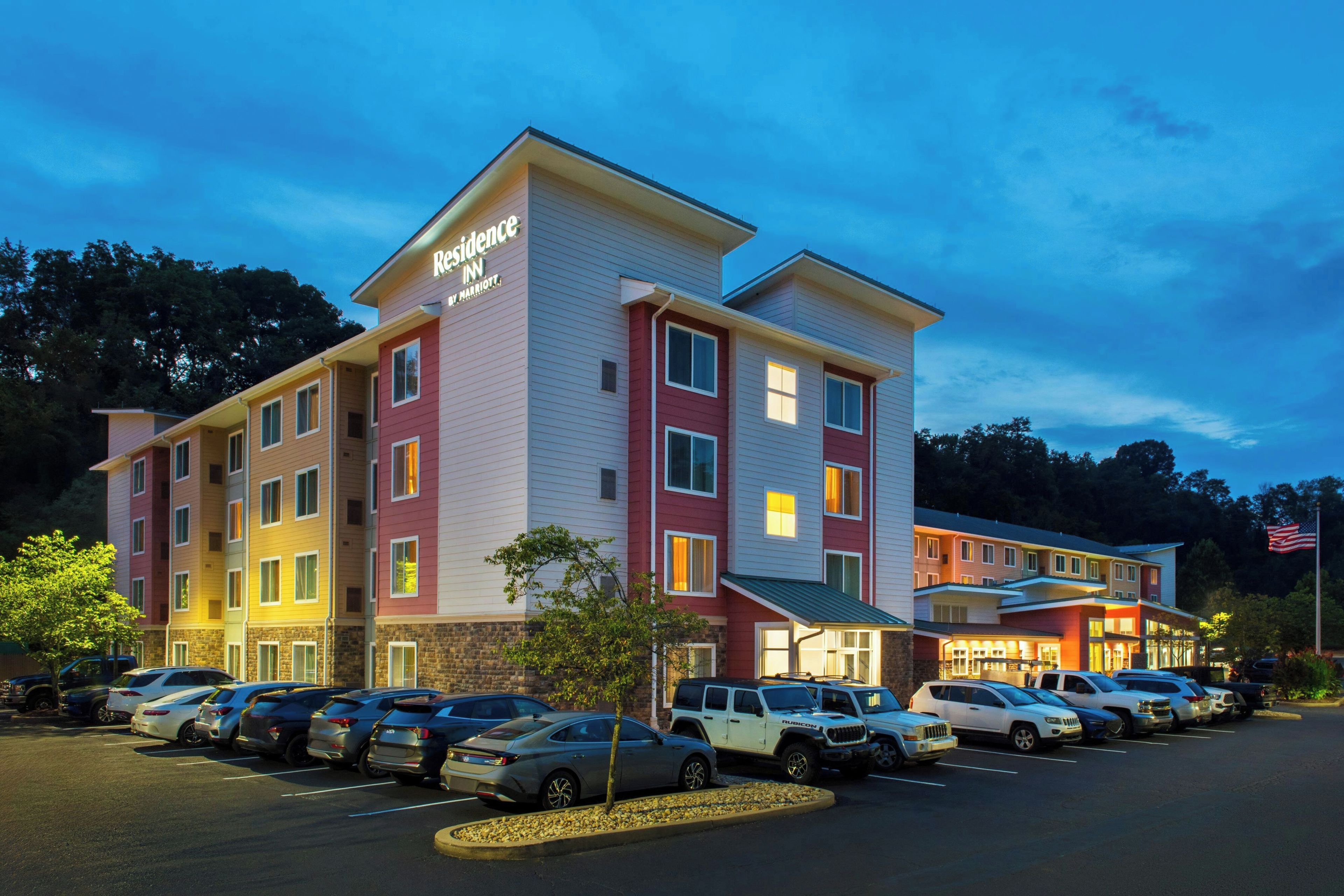 A multi-story hotel with a parking lot full of cars.