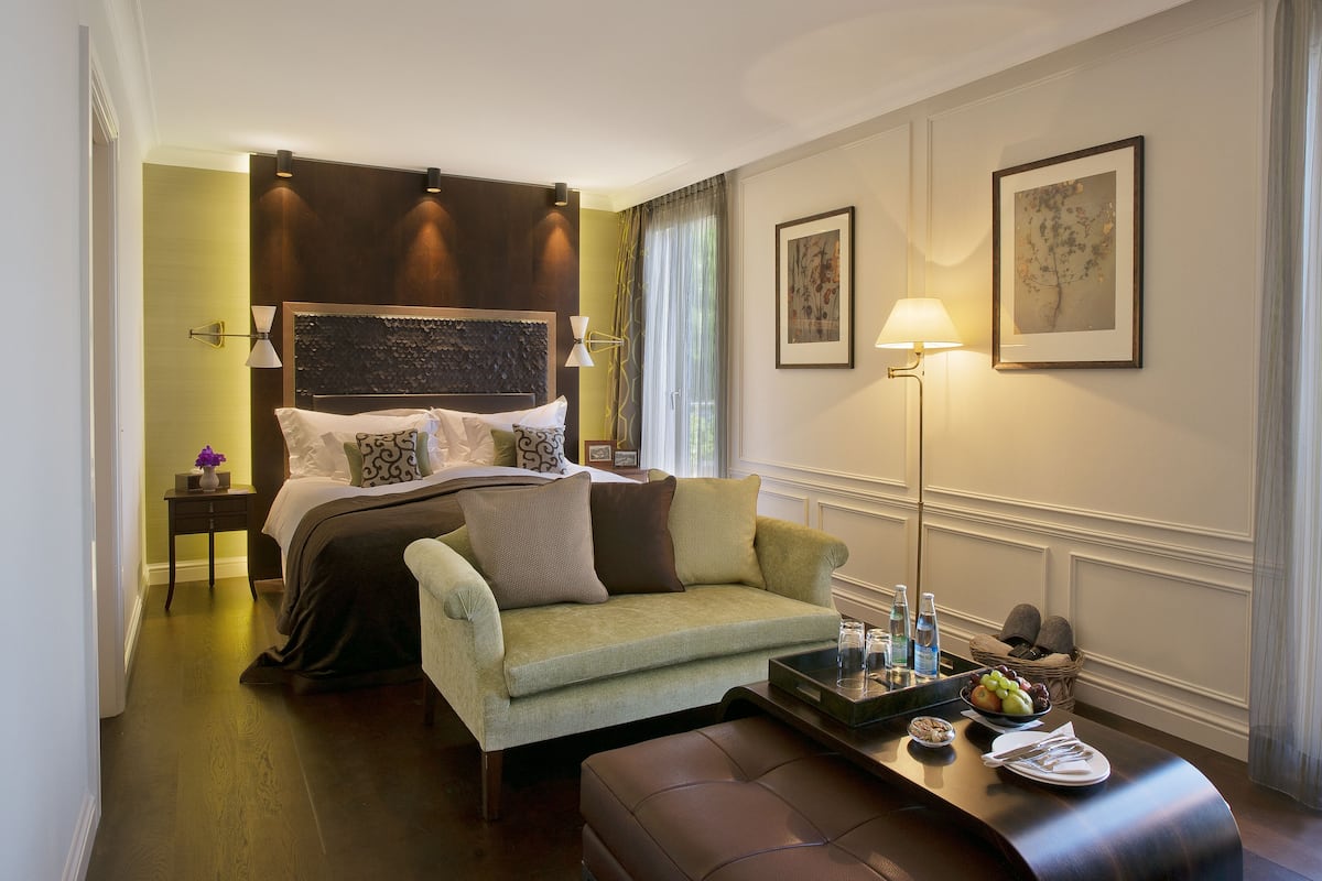A hotel room with a bed, a sofa, a coffee table, and a lamp.