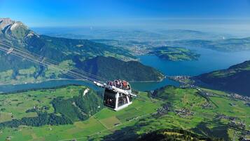 Une télécabine transportant des passagers, survolant un paysage montagneux avec un lac en contrebas.