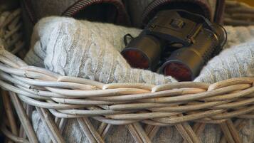 A wicker basket containing a pair of shoes and a metallic object.