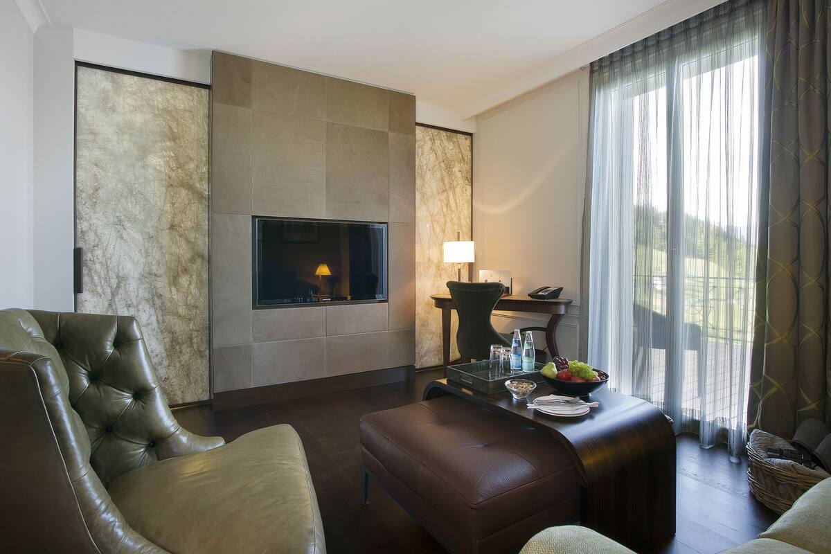 A modern living room with a fireplace, leather furniture, and a dining area with a table set for two.