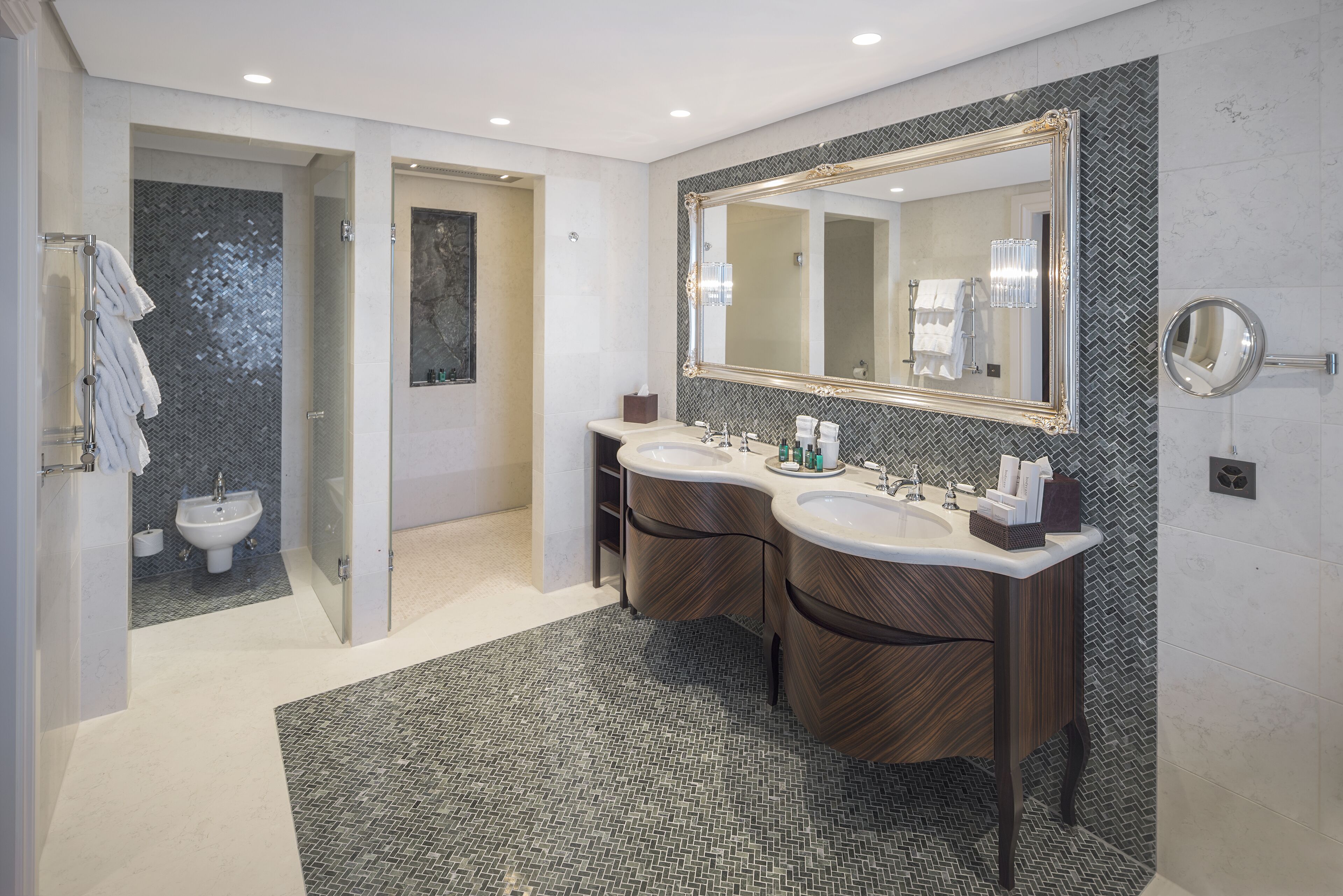 A modern bathroom with two sinks, a large mirror, and a shower area.