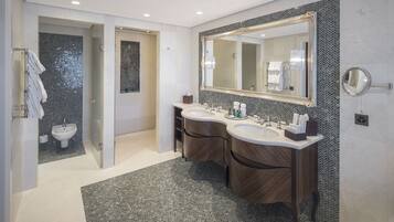 A modern bathroom with two sinks, a large mirror, and a shower area.