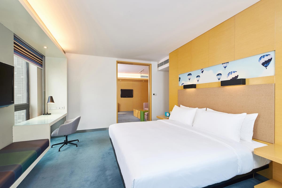 Een hotelkamer met een groot bed, een bureau met stoel, een televisie en een kunstwerk aan de muur.