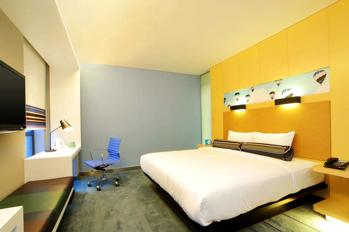 Une chambre d’hôtel avec un lit, un bureau, une chaise et un téléviseur.