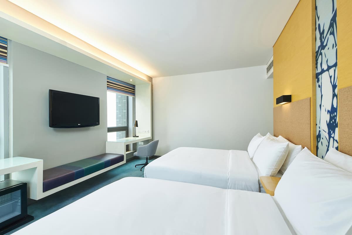 Een hotelkamer met twee bedden, een bureau, een stoel, een flatscreen televisie en een raam met jaloezieën.