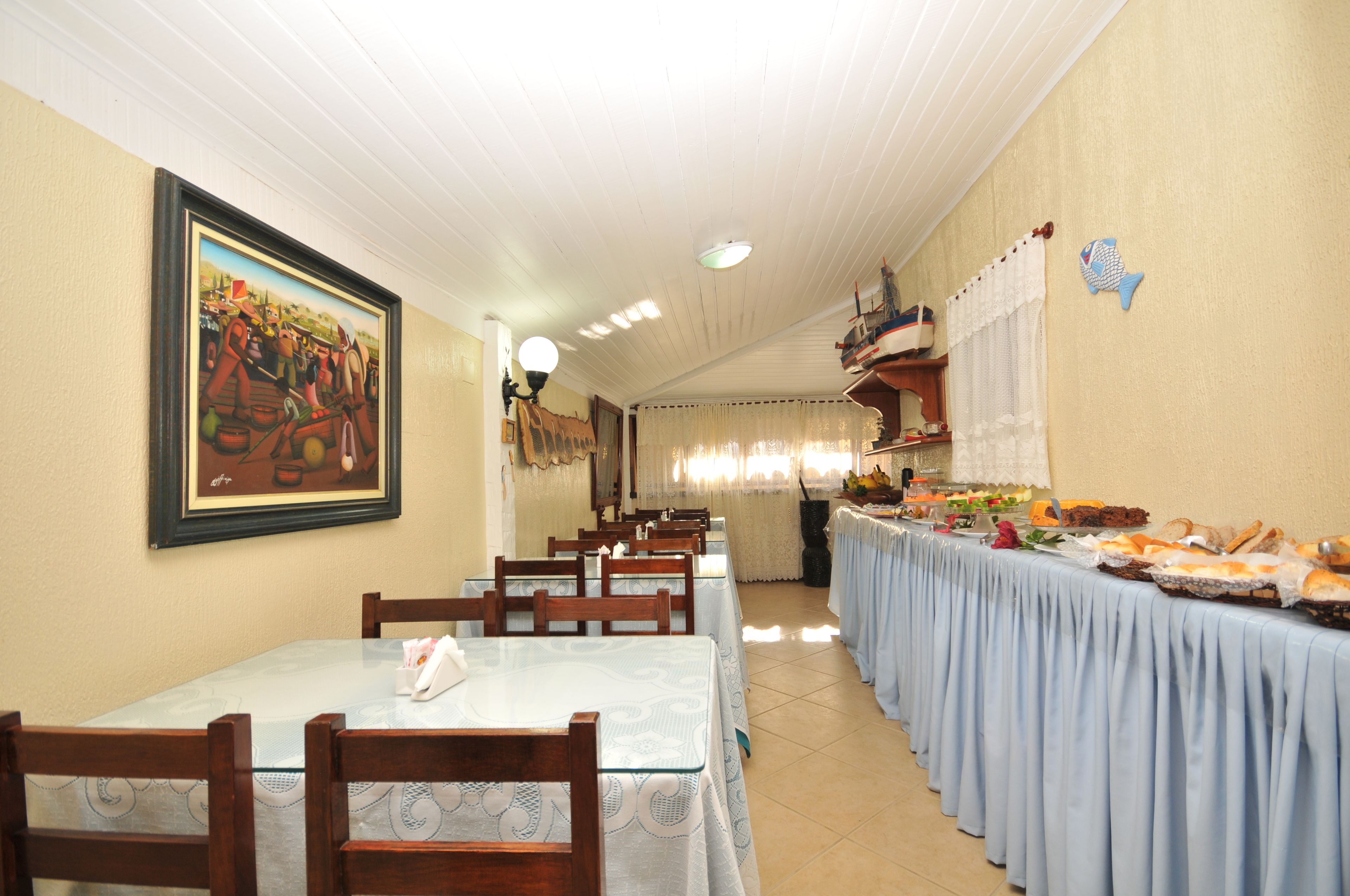 A dining area with tables and chairs, a buffet with various food items, and a painting on the wall.