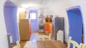 Una cocina compacta con una mesa y sillas de madera, estufa, microondas y refrigerador.