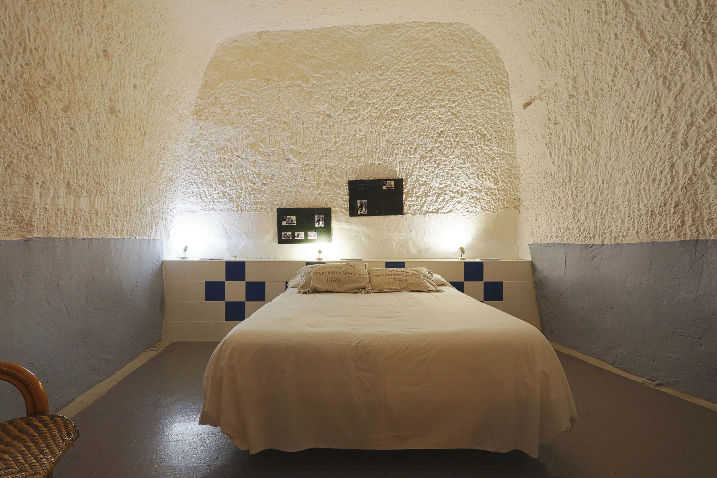 Un dormitorio con una cama grande, una silla y una pared con textura.