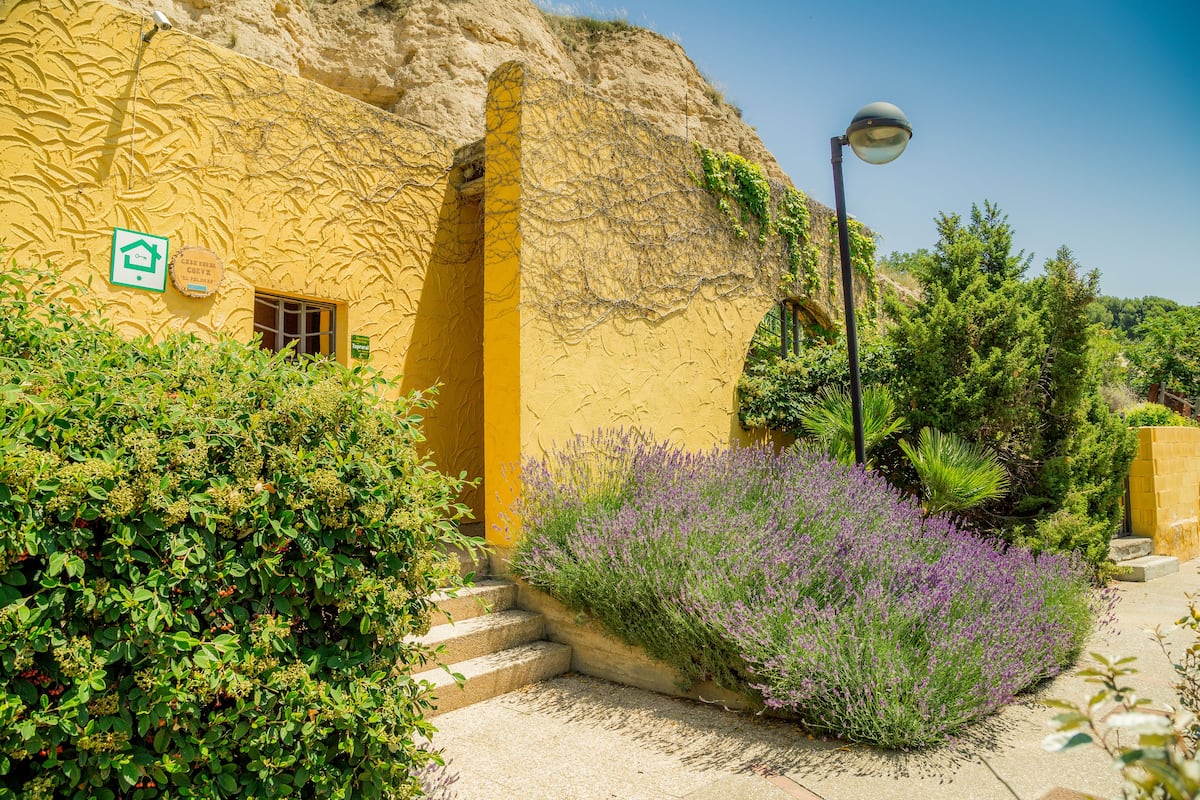 A yellow building with a stone archway, a door, and a sign indicating a house.