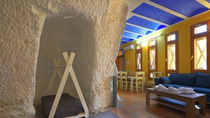 Una habitación con pared de piedra, un banco de madera, un sofá azul y una mesa con toallas.