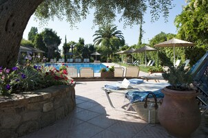 Una piscina al aire libre, sombrillas, sillones reclinables de piscina