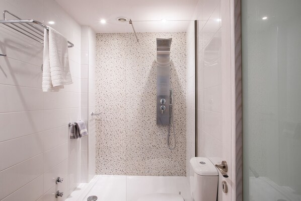 Une salle de bain moderne équipée d’une douche, de toilettes et d’un porte-serviettes.