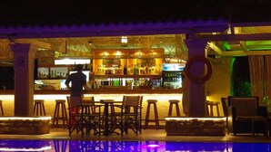 Een bar met krukjes en een zwembad dat het interieur van de bar weerspiegelt.