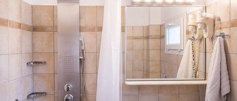 Baño con ducha, lavamanos y espejo con luces superiores.