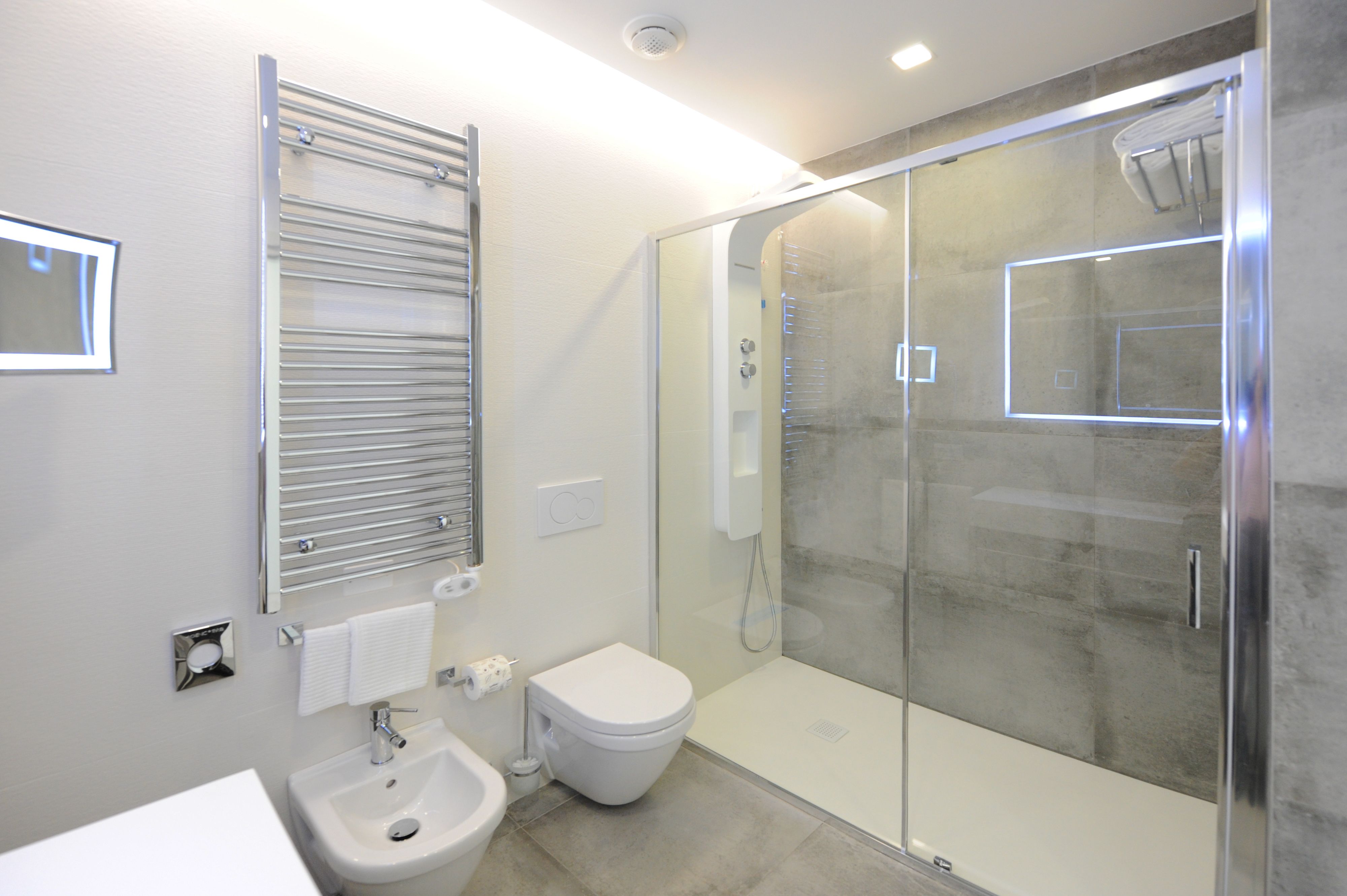Un baño moderno con ducha de vidrio, lavamanos blanco y retrete.