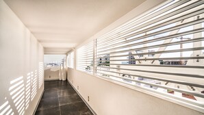 Een gang met een modern ontwerp, bestaande uit een lange, smalle ruimte met een betegelde vloer en een balustrade met horizontale spijlen.