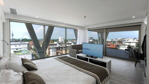 Een moderne hotelkamer met een groot bed, een flatscreen televisie en een balkon met uitzicht op de stad.