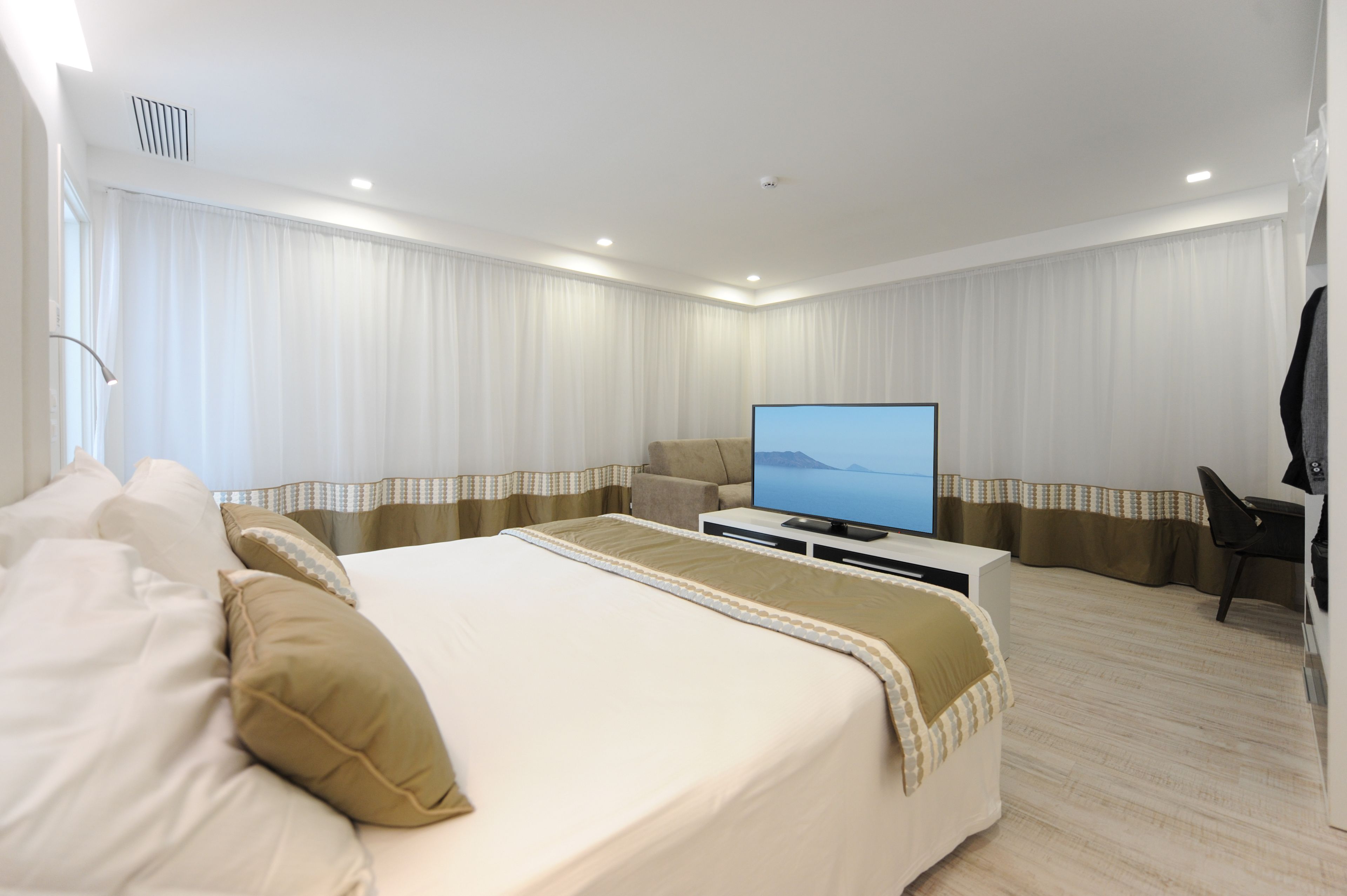 Une chambre d’hôtel avec un grand lit, un téléviseur à écran plat, un bureau et une chaise.