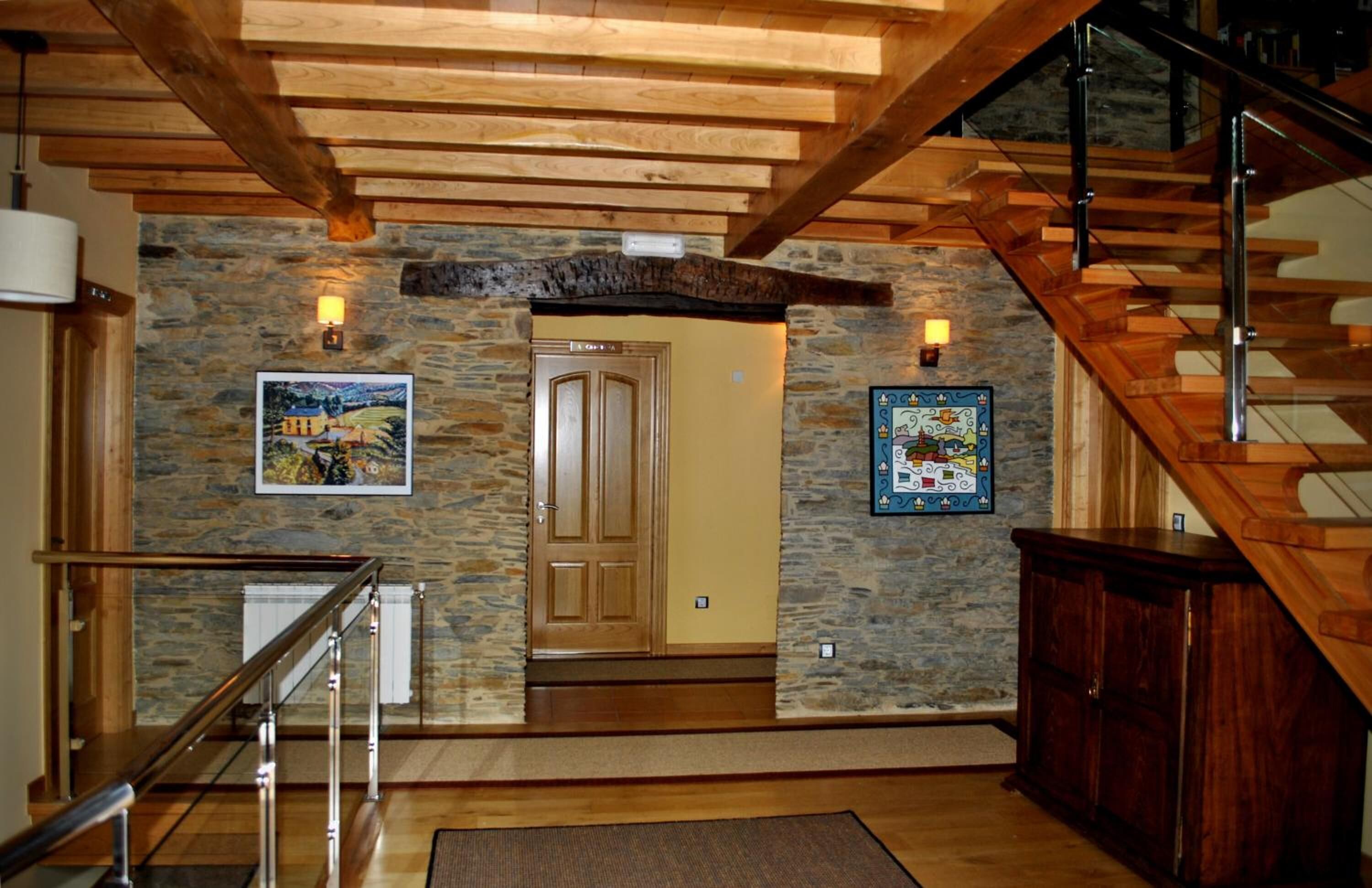Una escalera de madera con barandillas de vidrio que conduce a un muro de piedra.