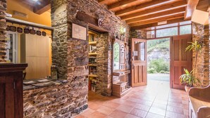 A rustic interior with stone walls, wooden beams, and a tiled floor.
