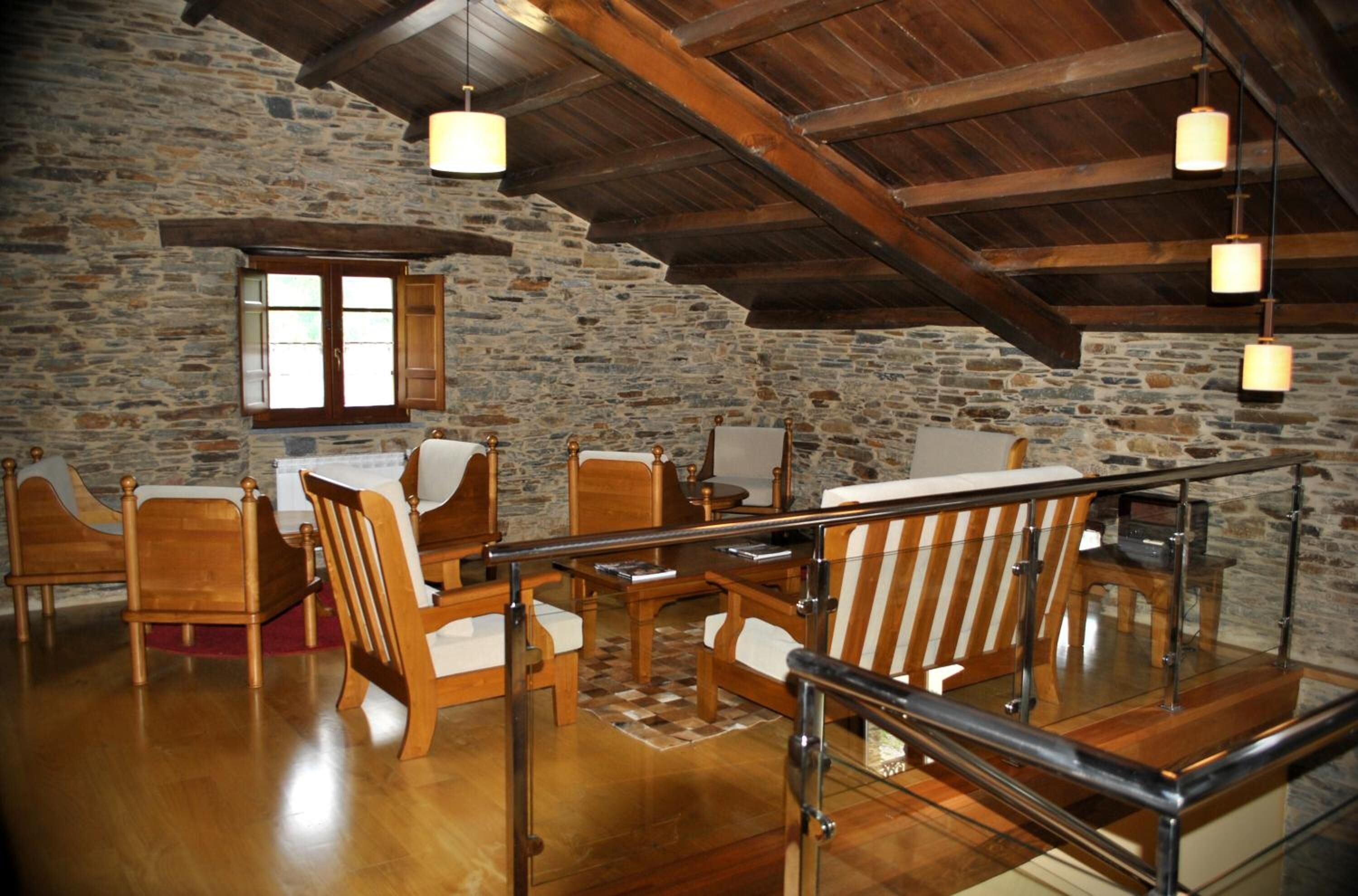 Una habitación rústica con paredes de piedra, muebles de madera y barandilla de cristal.