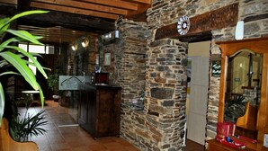 A rustic interior with stone walls, wooden beams, and a bar area.