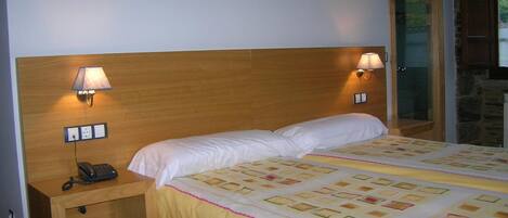 A hotel room with a wooden headboard, two bedside lamps, a telephone, and a bed with a patterned bedspread.
