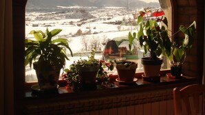 A view through a window with a brick arch, displaying a snowy landscape with mountains and a clear sky. - Hotel El Churron (Sabinanigo)
