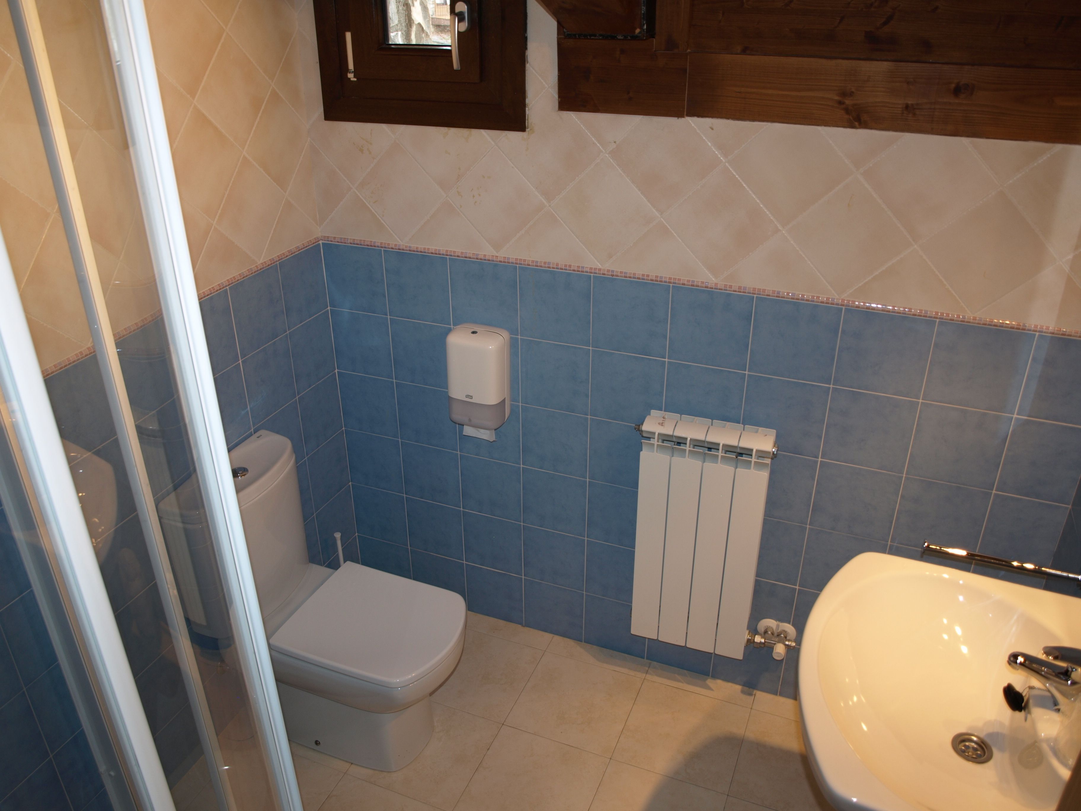 A bathroom with a toilet, a hand dryer, a radiator, and a sink.