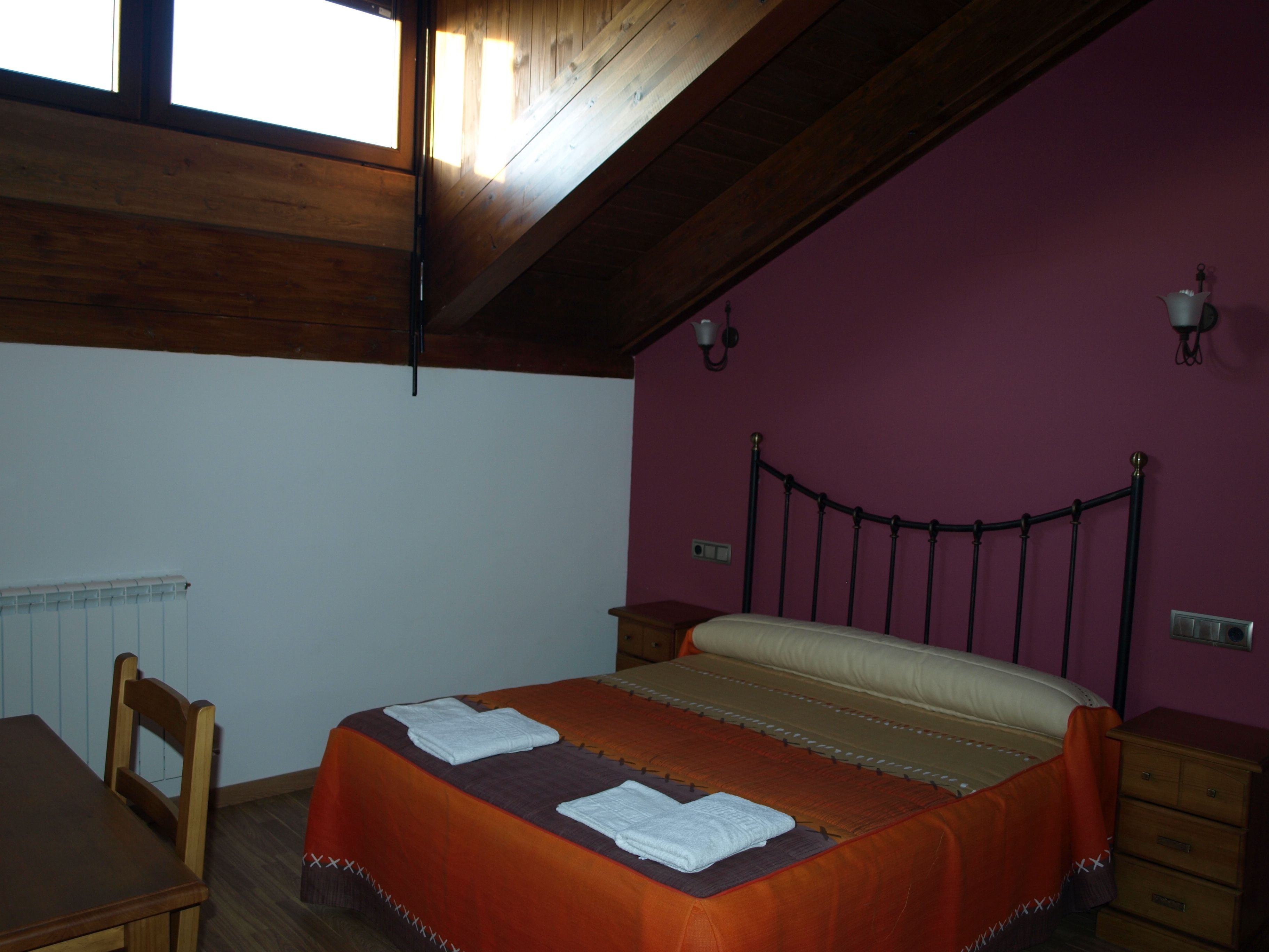 A bedroom with a bed, wooden furniture, a window, and a purple wall.
