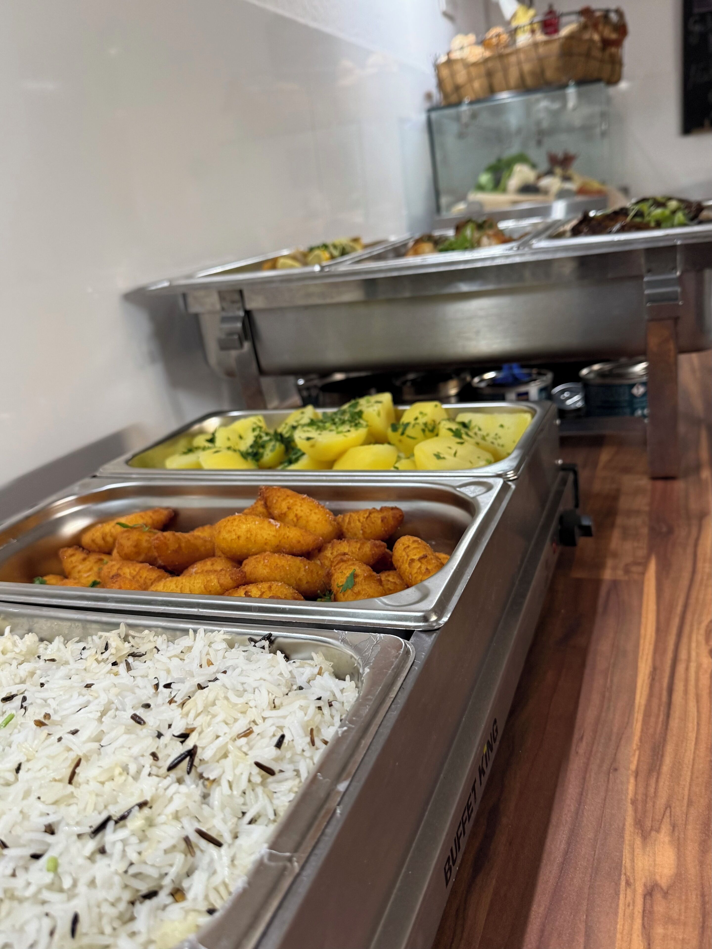 Un bufé con diferentes opciones de comida, incluyendo arroz, papas y aperitivos fritos.