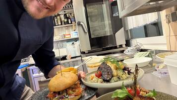 A person holding a plate with a sandwich and a bowl of salad.