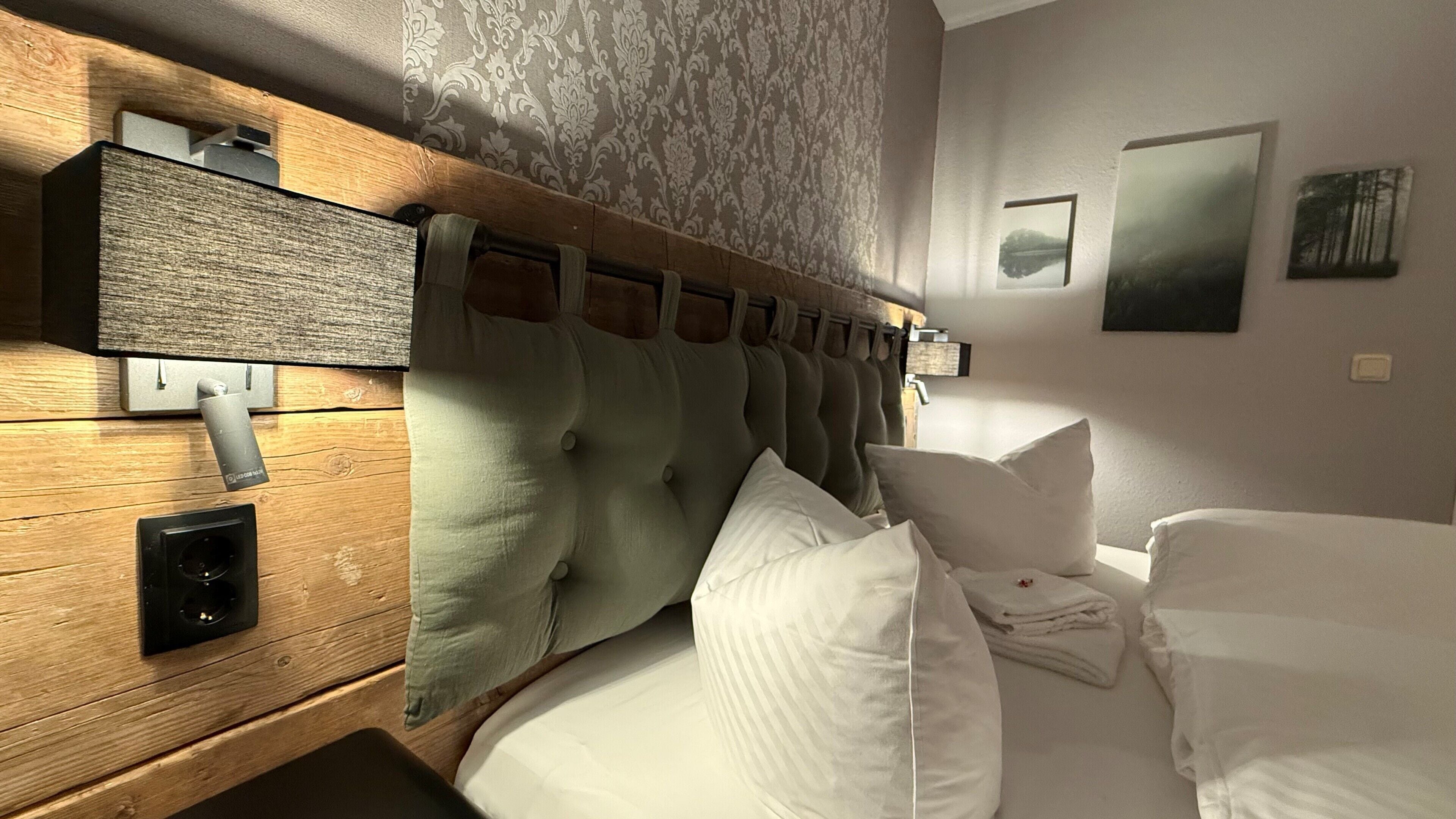 A hotel room with a wooden headboard, a built-in speaker, and a bed with white linens.