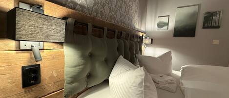 A hotel room with a wooden headboard, a built-in speaker, and a bed with white linens.