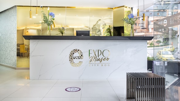 A modern reception desk with a marble counter, glass panels, and decorative plants.