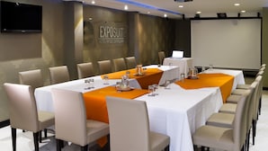 A conference room with a long table, multiple chairs, and a projector screen.