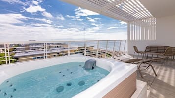 A rooftop terrace with a hot tub, outdoor seating, and a view of the cityscape.