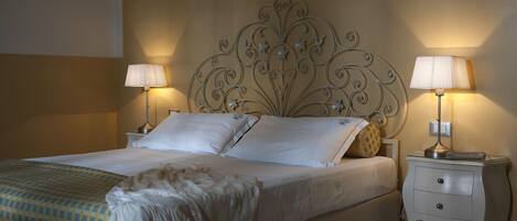 A neatly made bed with white linens and a decorative headboard, flanked by two bedside tables with lamps.
