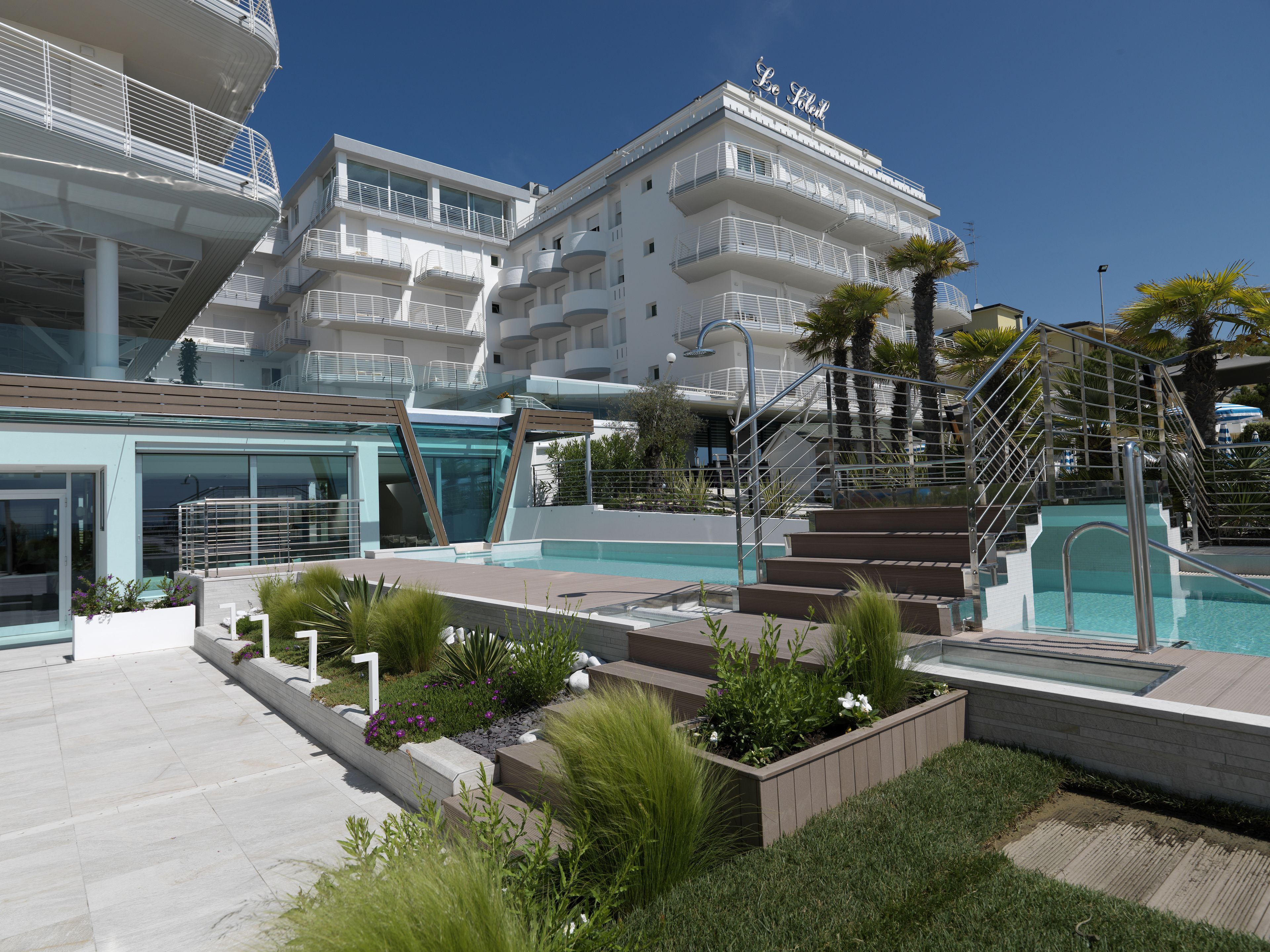 Een modern hotel met een zwembad, terras en een trap naar de bovenverdiepingen.