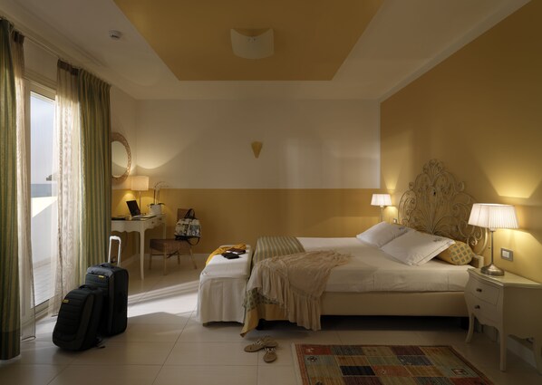 Habitación de hotel con cama, mesitas de noche, escritorio, silla, maleta y alfombra.