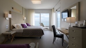 A modern hotel room with a bed, desk, chair, and a view of the sea. - Hotel Le Soleil (Jesolo)
