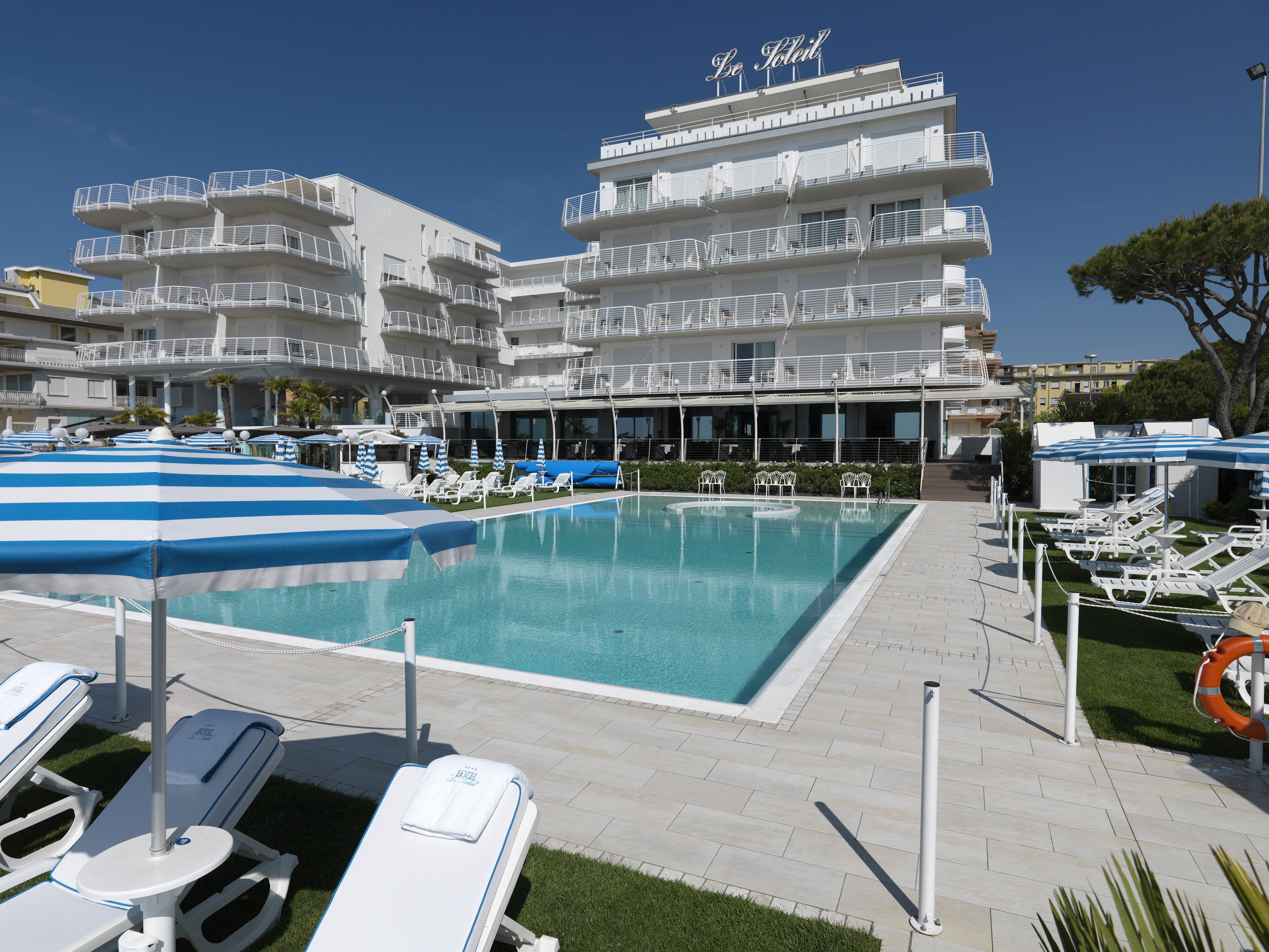 Un hôtel doté d’une piscine, de plusieurs balcons et de chaises longues.