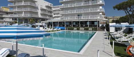 Un hotel con zona de piscina, varios balcones y sillas de descanso.