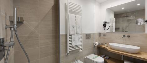 A modern bathroom with a glass-enclosed shower, a bidet, a large sink, and a mirror.