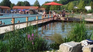 A public swimming area with a wooden bridge, a pool, and surrounding greenery. - Haus am Markt (Königstein)